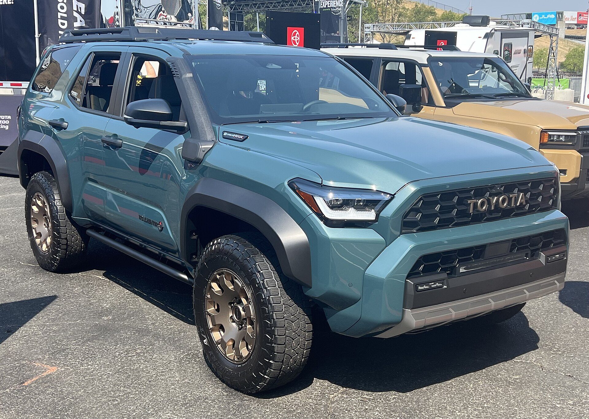 Green sixth-generation 4Runner Trailhunter with its high-mounted air intake, roof rack and bronze wheels parked on display at Sonoma Raceway