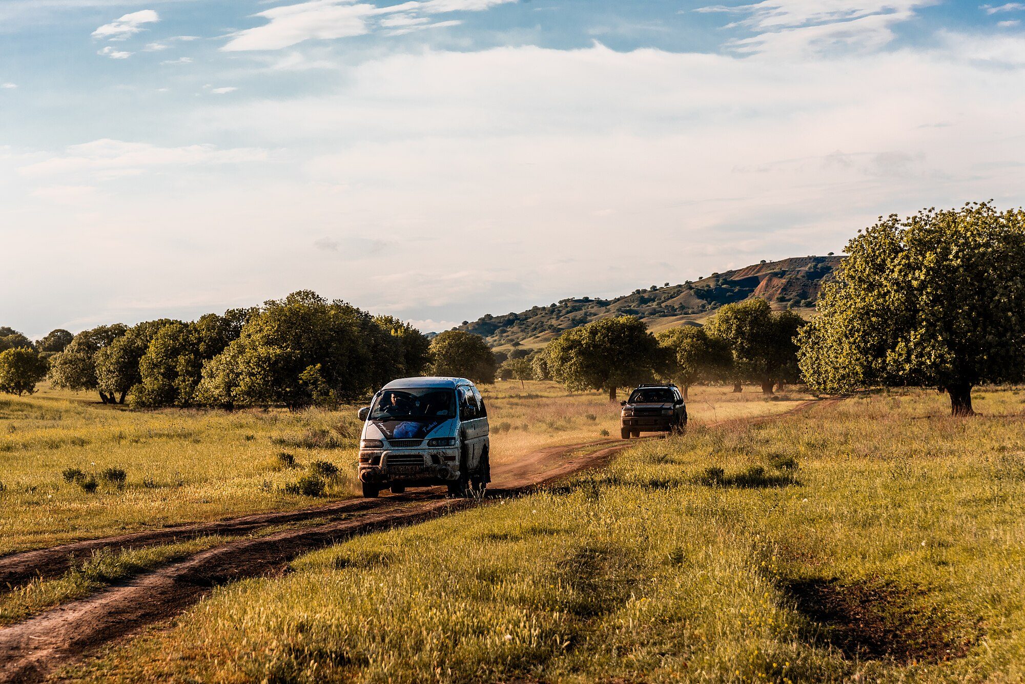 A mud-splashed Delica Space Gear driving a dirt two-track through the grassland of Vashlovani, Georgia, with another 4x4 behind
