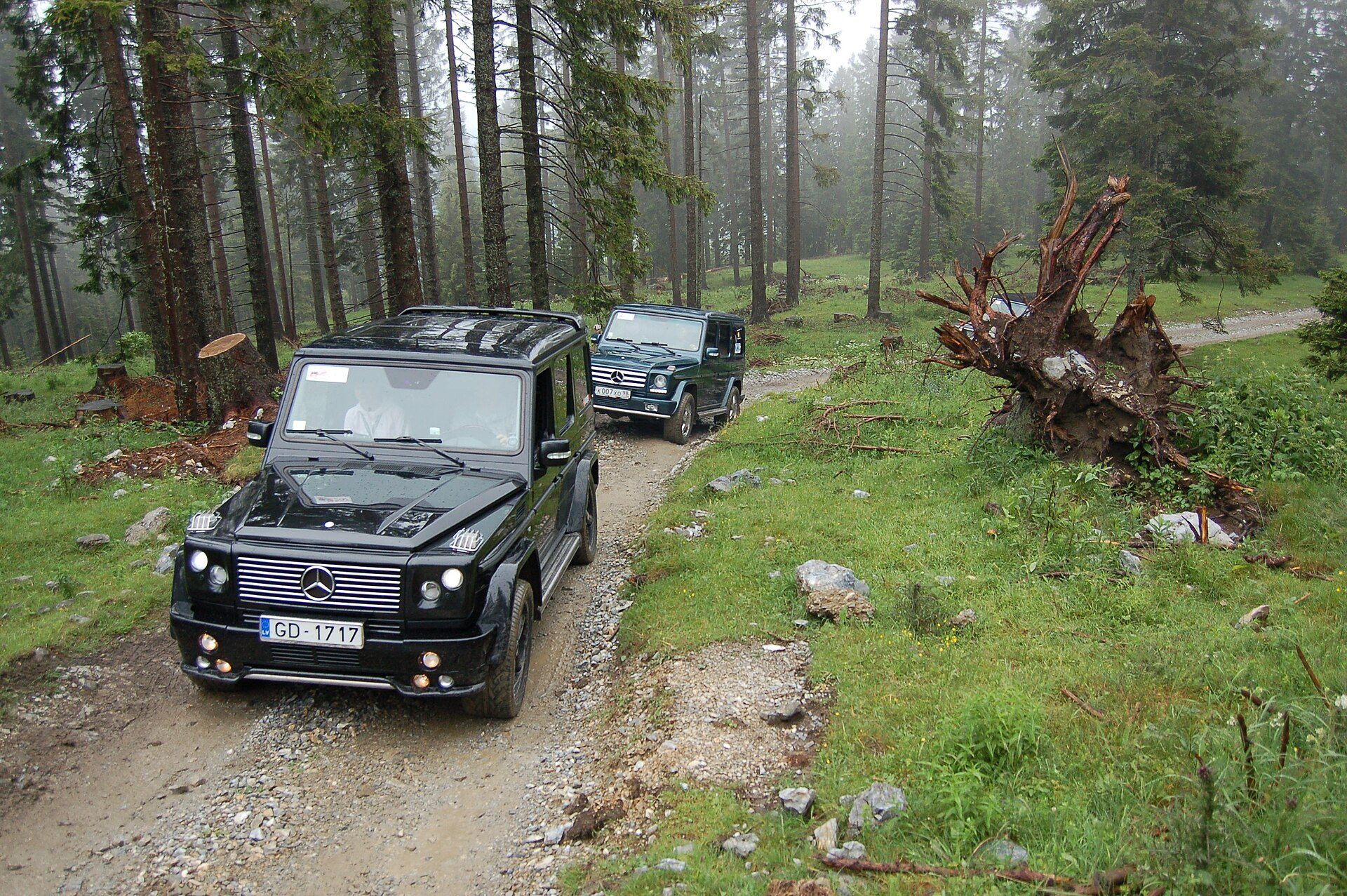 A black G 55 AMG leading a second G-Class down a rocky forest track on the Schöckl