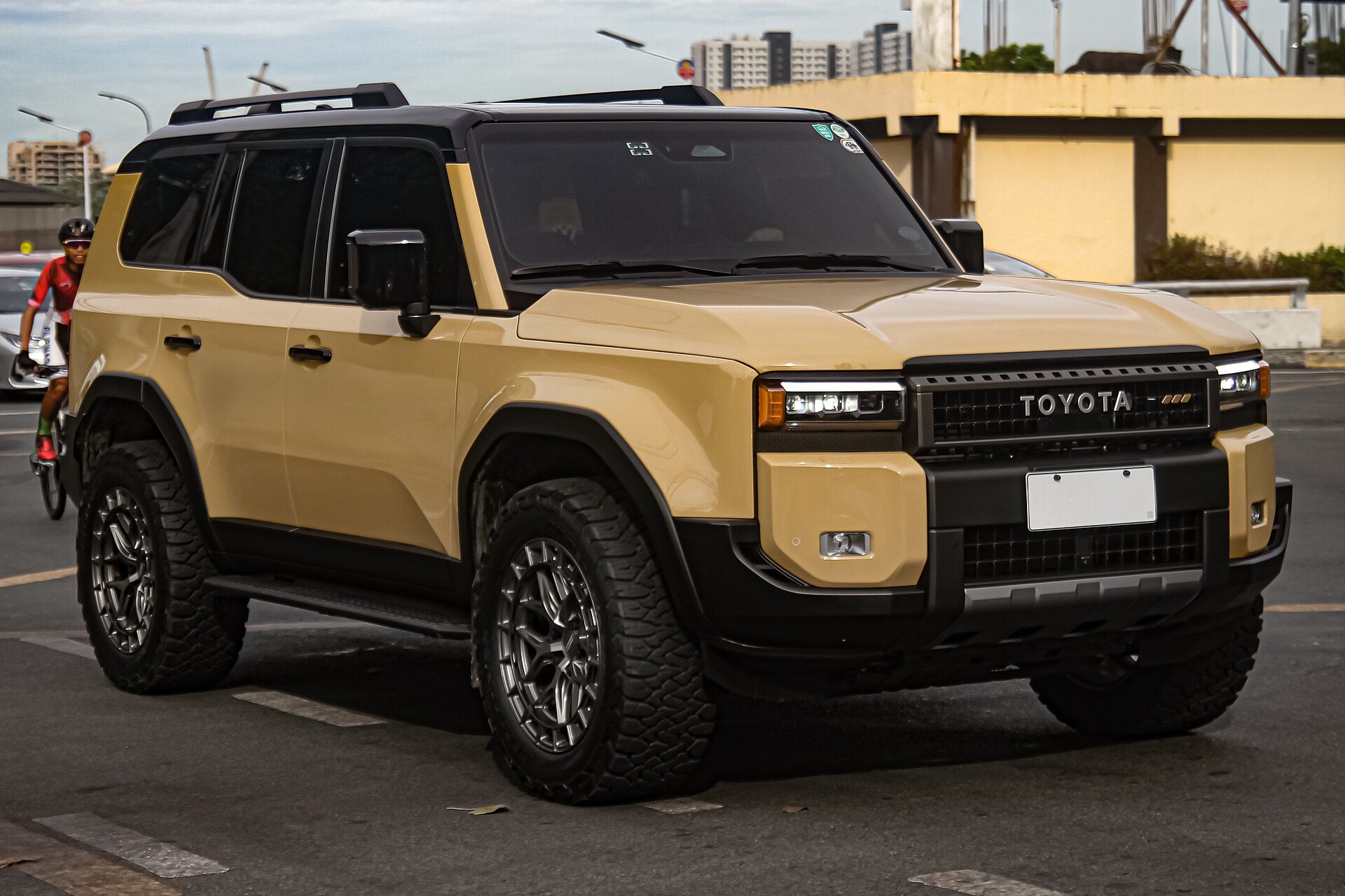 A Trail Dust and black two-tone 250 Series Land Cruiser on a city street