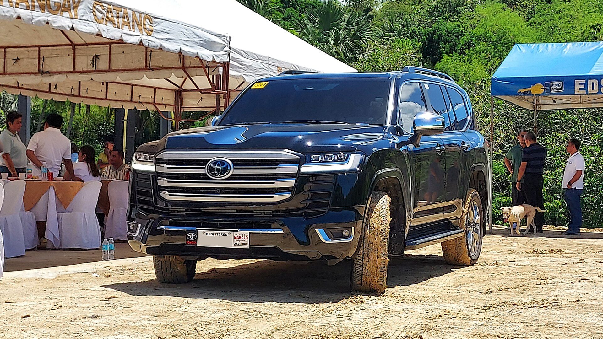 A black 300 Series Land Cruiser with muddy tyres parked on a dirt lot at an outdoor event in the Philippines