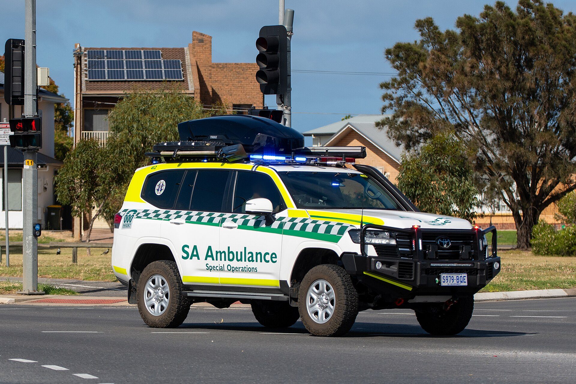 A South Australian Ambulance Special Operations 300 Series Land Cruiser with bull bar, roof rack, light bar and all-terrain tyres at a city intersection