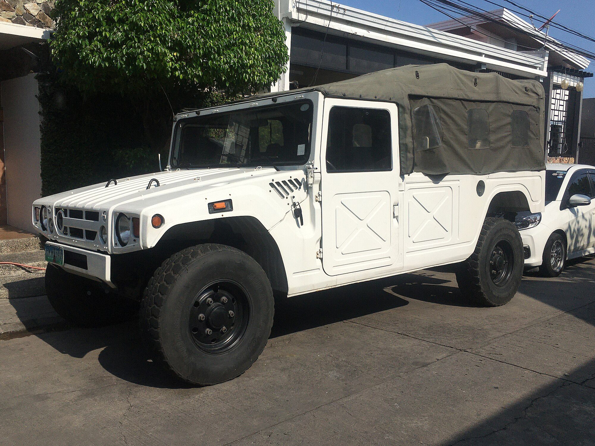 A white ex-military Toyota Mega Cruiser BXD10 with an olive canvas rear top parked by a house in Las Piñas, Metro Manila