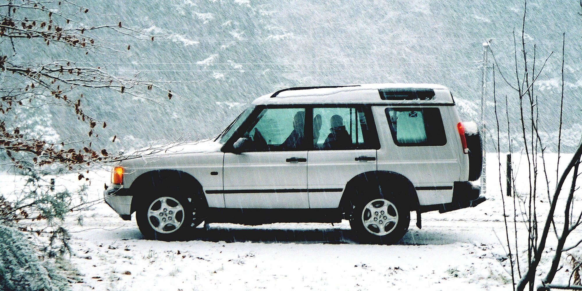 A white 2000 Discovery Series II Td5 ES parked in falling snow in rural Morayshire, Scotland
