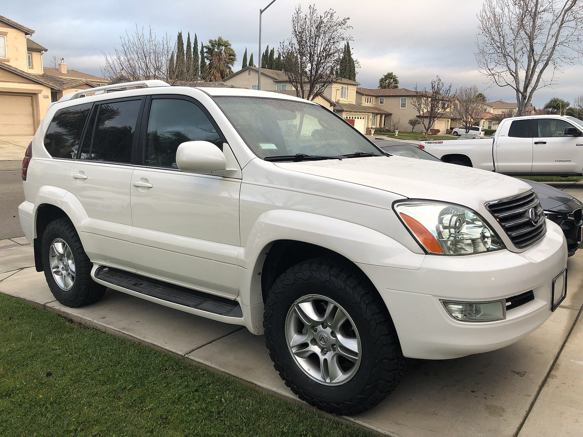 A pearl-white 2007 Lexus GX 470 parked at the kerb with a lawn behind