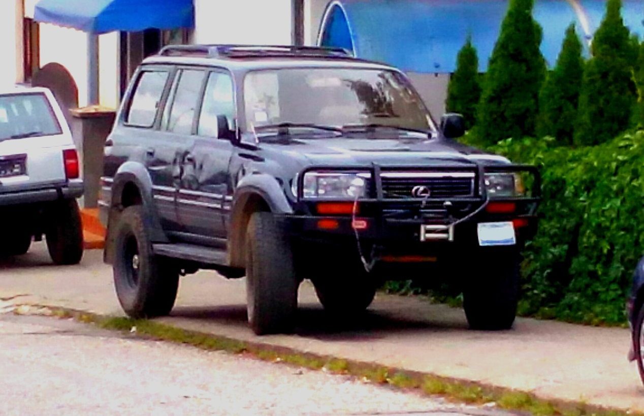 A black Lexus LX 450 modified for off-road use with a steel bull bar, winch and lift