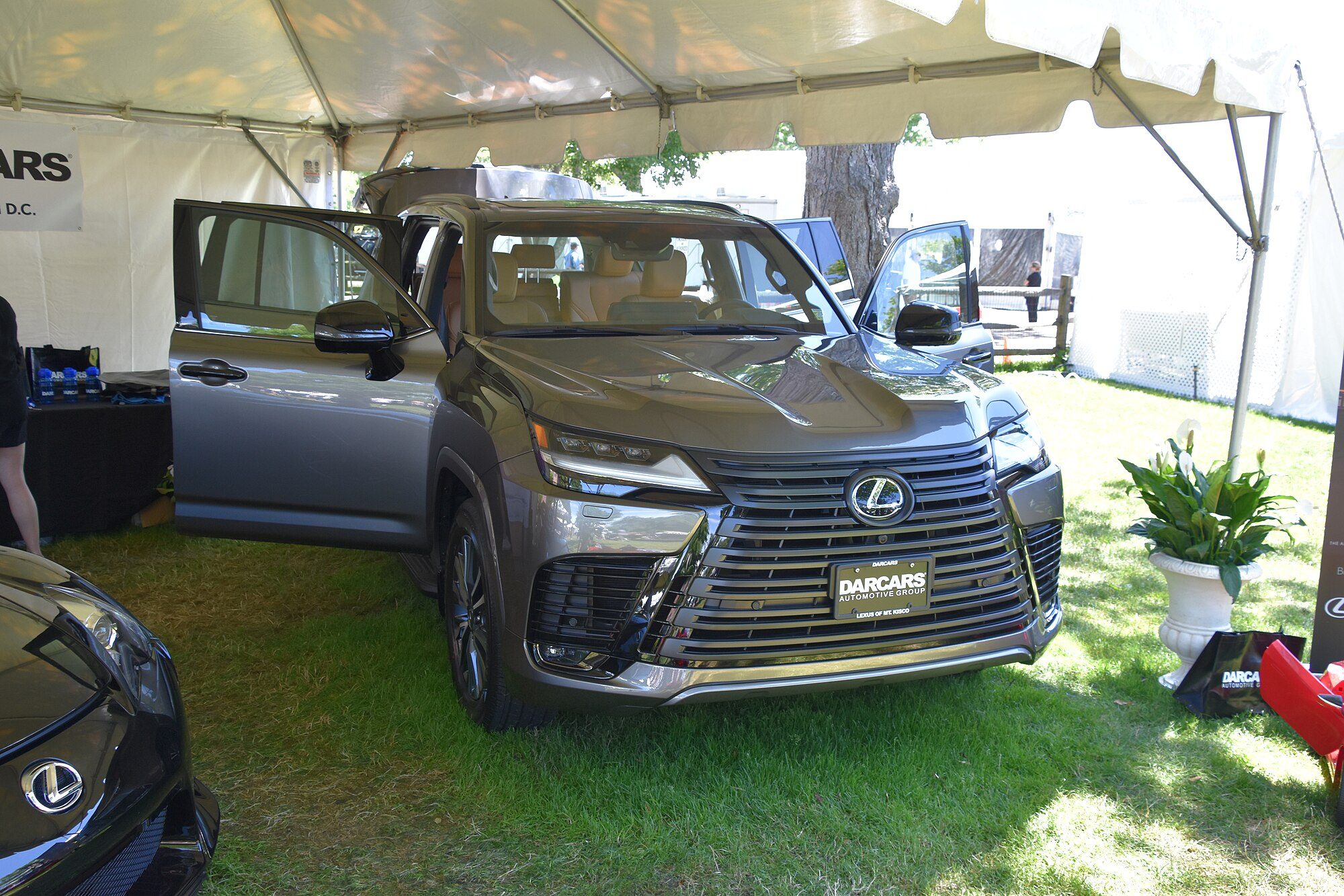 A grey 2022 Lexus LX 600 on grass under a display tent