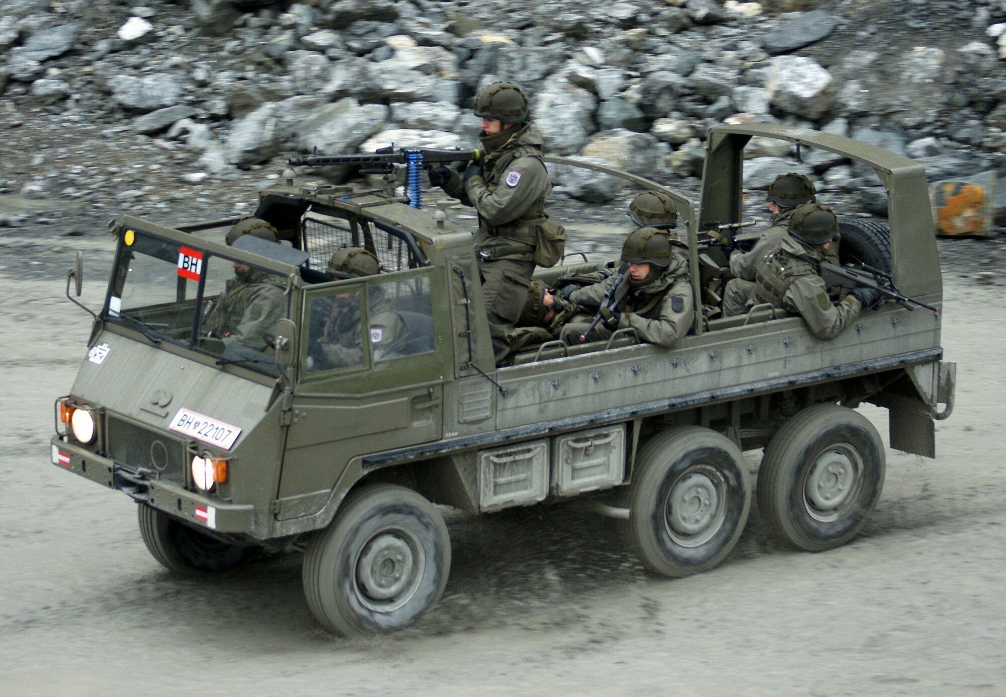 An Austrian Army Pinzgauer 712M 6x6 carrying soldiers across the floor of a rocky quarry