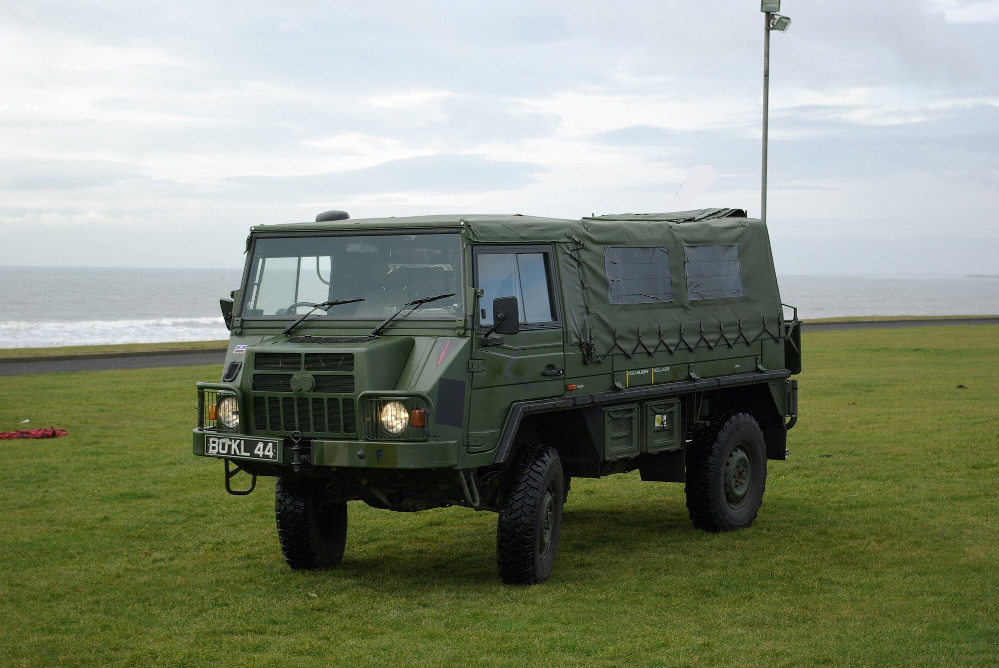 A British Army Pinzgauer 716M soft-top turbo-diesel parked on coastal grass