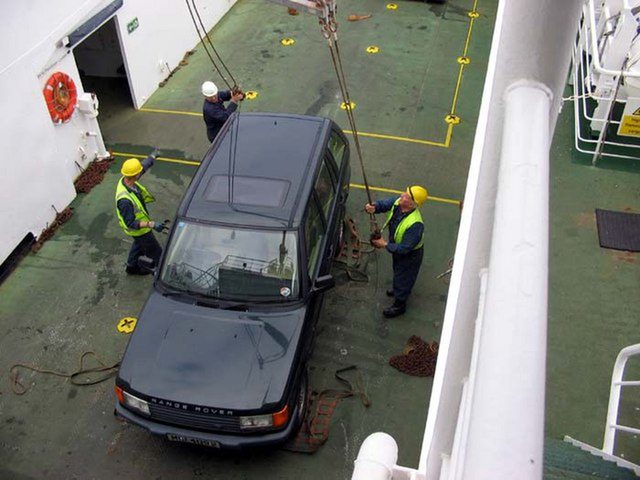 Crew untying a dark P38A Range Rover after it was lifted aboard the Papa Westray ferry in Orkney