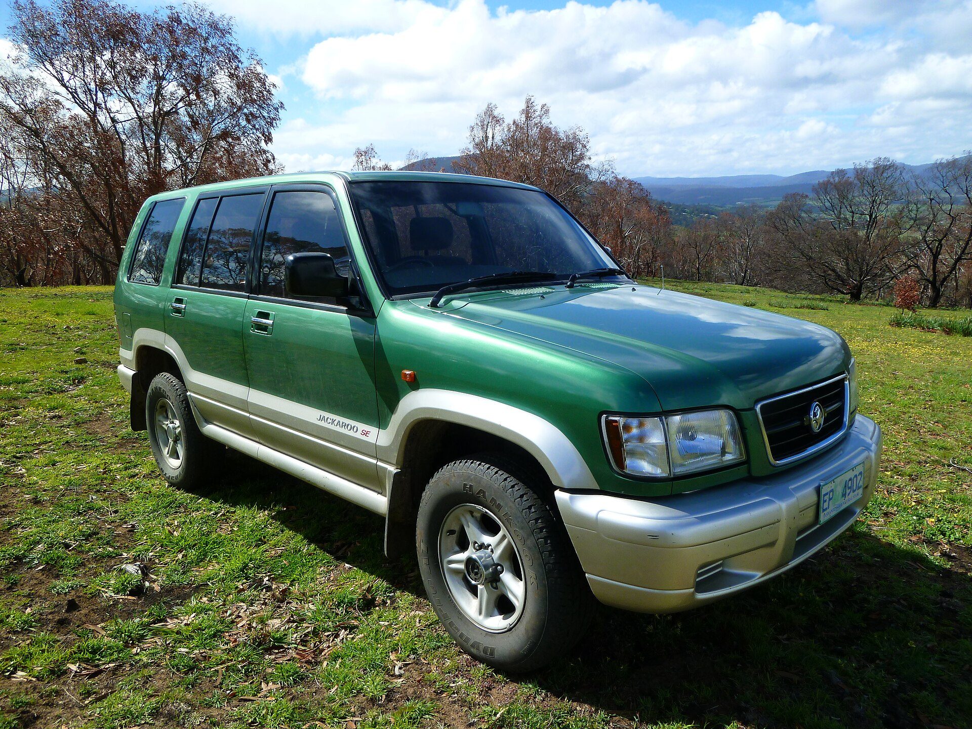 A green and silver 2000 Holden Jackaroo SE, the Australian second-generation Trooper, parked on a grassy hillside in Tasmania